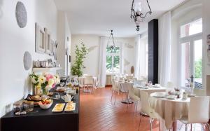 加尔达湖滨埃尔伯格加尔尼莫雷蒂别墅酒店的用餐室配有白色的桌子和白色的椅子