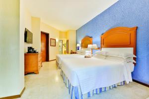 坎昆Occidental Tucancún - All Inclusive的一间卧室设有两张床和蓝色的墙壁