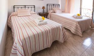 瓜达卢佩阿尔巴塔鲁塔旅馆的卧室内的两张床,配有毛巾和鲜花