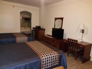 麦卡伦Texas Inn Downtown McAllen的酒店客房设有两张床、一张桌子和一面镜子