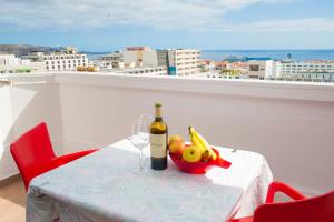 美洲海滩playa honda的一张桌子,上面放着一瓶葡萄酒和一碗水果