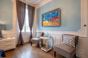 Bligny-lès-Beaune朱莉和莉莉里斯克尔酒店的一间设有两把椅子和一张桌子的房间,还有一幅画
