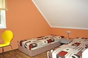 卡尔斯哈根Ferienwohnungen Karlshagen USE 3010的橙色墙壁和黄色椅子的客房内的两张床