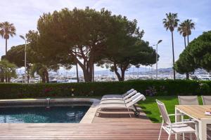 戛纳FRGK"Contemporary Villa on the Croisette with Stunning Sea Views & Private Pool!!!的一个带椅子和桌子的游泳池以及树木