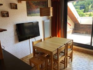 昂塞勒Duplex 6 à 8 couchages calme avec solarium plein Sud的客厅配有木桌和平面电视。