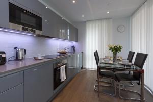 伦敦伦敦中央豪华公寓的厨房配有玻璃桌和黑色椅子