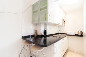福恩吉罗拉PYR Private Apartment SUNNY pool SIDE的厨房配有白色橱柜和黑色台面