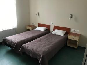 派尔努赫玛库宾馆的配有两张桌子和一扇窗户的客房内的两张床