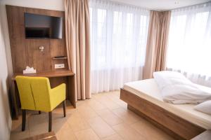Uznach舒琛豪斯酒店的一间卧室配有一张床、一张桌子和一张黄椅