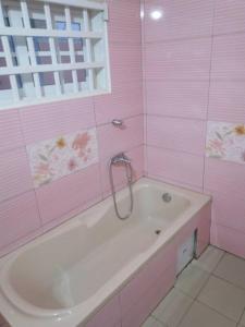 洛美MINI VILLA ROSE的粉红色的浴室设有浴缸和窗户。