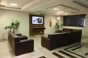 阿帕雷西达Ouro Minas Plaza Hotel的带沙发和平板电视的等候室