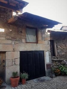 MontezinhoAbrigo Montesinho的一座石头房子,设有黑色的门和窗户