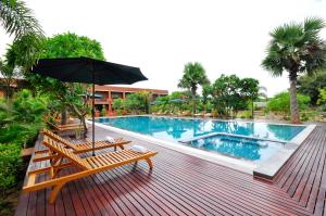 蒲甘Bagan Wynn Hotel的甲板上设有带长椅和遮阳伞的游泳池