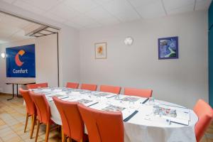 蒙吕松Comfort Hotel Montlucon的一间会议室,配有长桌子和橙色椅子
