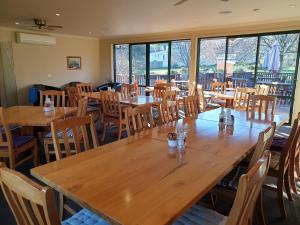 Roxburgh罗克斯堡湖旅舍的餐厅设有木桌、椅子和窗户。