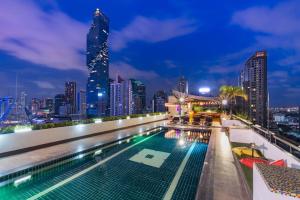 曼谷Furama Silom Hotel的一座城市天际线建筑屋顶上的游泳池