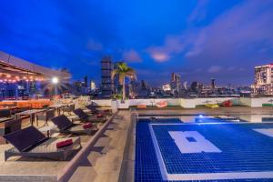 曼谷Furama Silom Hotel的一个带椅子的屋顶游泳池和城市天际线
