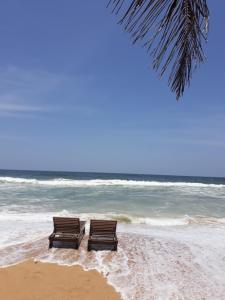 因都鲁瓦Arcade Beach Hotel的两个长椅坐在海边