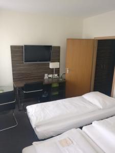 纽伦堡纽伦堡贝林尔斯城市酒店的酒店客房设有两张床、一张桌子和一台电视。