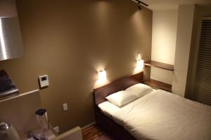 箱根Condominium MIRAHAKONE的卧室配有一张床,墙上有两盏灯