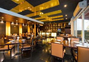 曼谷素坤逸富丽华阿索克酒店的餐厅设有木桌、椅子和大窗户。