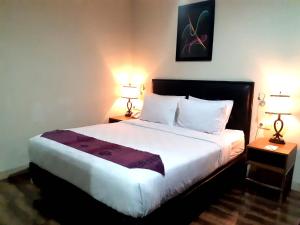 安汶Pacific Hotel Ambon的一间卧室配有一张大床和两盏灯
