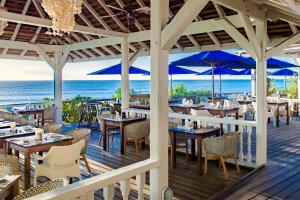 Johnsons PointCocobay Resort Antigua - All Inclusive - Adults Only的海滩上的餐厅,配有桌子和蓝伞