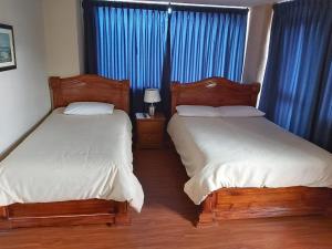 基多途塔曼达2旅馆的卧室内的两张床,配有蓝色窗帘