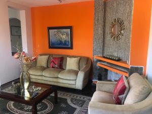 基多途塔曼达2旅馆的客厅设有两张沙发和一个橙色的墙壁