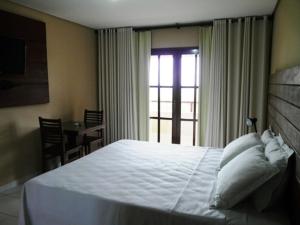 特里温福Pousada Calugi的卧室设有一张白色大床和一扇窗户。