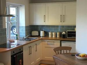 格拉斯顿伯里Littlemead - Newly renovated private studio near Glastonbury的厨房配有白色橱柜和木桌