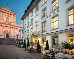 索洛图恩王冠精品酒店的一座白色的大建筑,庭院里设有桌椅