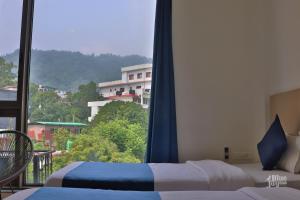 瑞诗凯诗Blue Jay Hostel Rishikesh的一间卧室设有两张床和大窗户