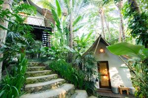 乌布乌布热带露营地的花园设有楼梯,通往棕榈树屋