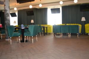 阿克托比Ayhan Hotel的一间带桌子和绿色椅子的用餐室