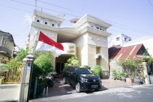 特尔纳特岛RedDoorz near Pantai Falajawa Ternate的停在有旗帜的建筑前面的汽车