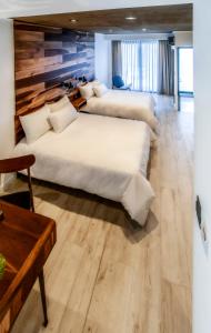 里奥夸尔托La Urumpta Hotel by AKEN Mind的铺有木地板的客房内的三张床