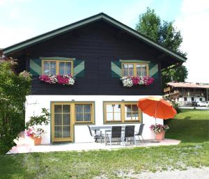 埃尔毛Alpen Chalet ELLMAU Zentrum的黑白房子,配有椅子和遮阳伞