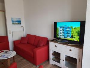 奥斯赛拜-塞林Studio 14 Strandmuschel, Residenz Seeblick的客厅配有红色沙发和平面电视