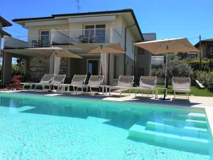 拉齐塞COSTA DEL GARDA - Lazise的一座房子,设有一座带椅子和遮阳伞的游泳池