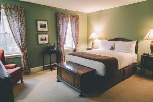 夏洛特顿伟大的乔治酒店的一间卧室配有一张床、一把椅子和窗户。