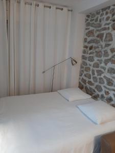 巴黎鸢尾花别墅旅馆 的一张白色的床,旁边是石墙边的灯