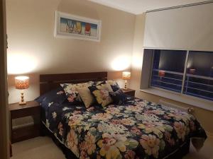 阿尔加罗沃Laguna Bahía, Algarrobo的一间卧室配有一张带花卉床罩和两盏灯的床。