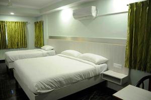 穆扎夫法尔普尔HOTEL CENTRAL SQUARE "A Couple Friendly Hotel"的酒店客房设有两张床和一张桌子。