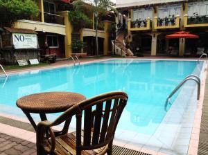 达沃市Crown Regency Residences Davao的游泳池旁的桌子和椅子