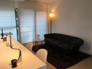 泽布吕赫Bel appartement Zeebruges的客厅配有黑色沙发和桌子