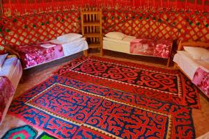 卡拉科尔Happy Nomads Yurt Camp & Hostel的一间设有两张床的房间和一张地毯
