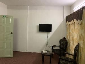 吉尔吉特Naveed Tourist Inn的配有电视、椅子和门的房间