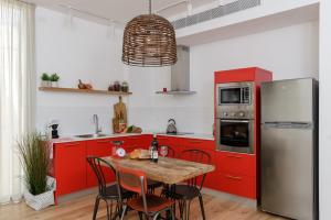 特拉维夫AirTLV - Rambam Residence W Private MAMAD!的厨房配有红色橱柜和桌椅
