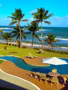 伊塔齐米林Apartamento beira-mar no Bali Bahia的拥有游泳池、棕榈树和海洋的度假酒店